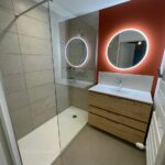 Salle de bain colorée avec douche et meuble vasque ave miroir rond