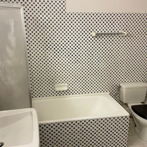 Salle de bain avec baignoire et WC avec carreaux à motifs.