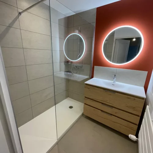 Salle de bain peinture orange miroir rond et douche à l'italienne