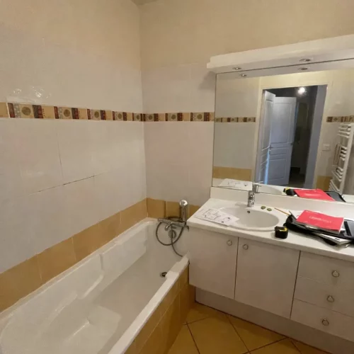 Salle de bain à rénover avec baignoire et meuble sous vasque blanc